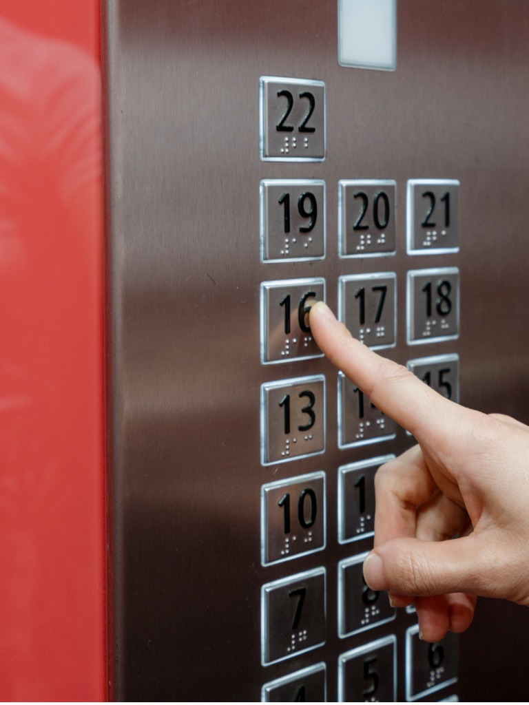 Close up of a women pressing floor 16 on a elevator